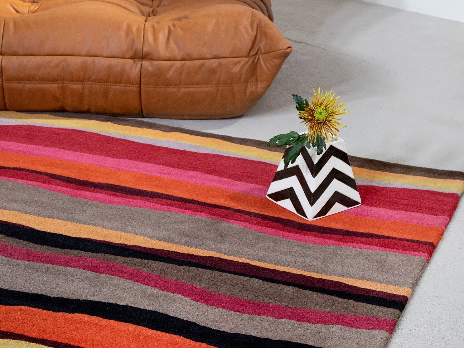 Alfombra de lana Estella Summer de Brink & Campman con un vibrante diseño de líneas onduladas en tonos cálidos y fríos, ideal para interiores contemporáneos.